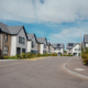 Springfield Homes development in Strathkinness — street view of stone and white render new-build detached homes with landscaped frontages